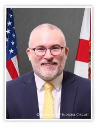 Portrait of Hearing Officer Patrick Vincent - - Gray background with the USA Flag on his right and the State of Florida Flag on his left